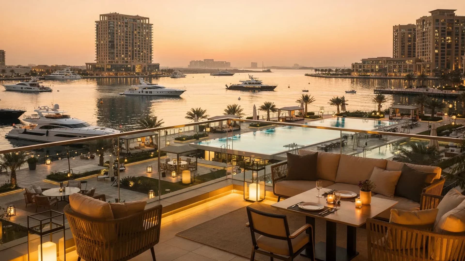 A luxury waterfront apartment balcony view in the UAE at sunset, with marina lights and resort-style amenities visible below, suggesting short-stay and premium long-let demand.